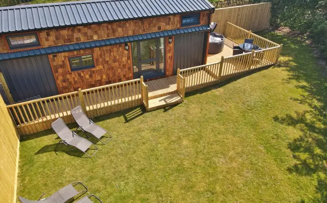 Walnut Lodge: A cosy tiny house for 4, with deck, hot tub, loungers, and a private lawn setting.