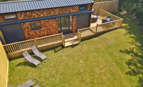 Walnut Lodge: A cosy tiny house for 4, with deck, hot tub, loungers, and a private lawn setting.